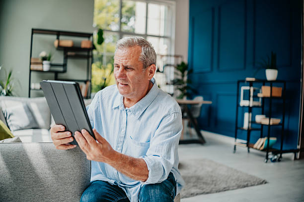 istock Senior man enjoying technology while relaxing at home, exploring the internet and smiling happily in a cozy living space 2227709410