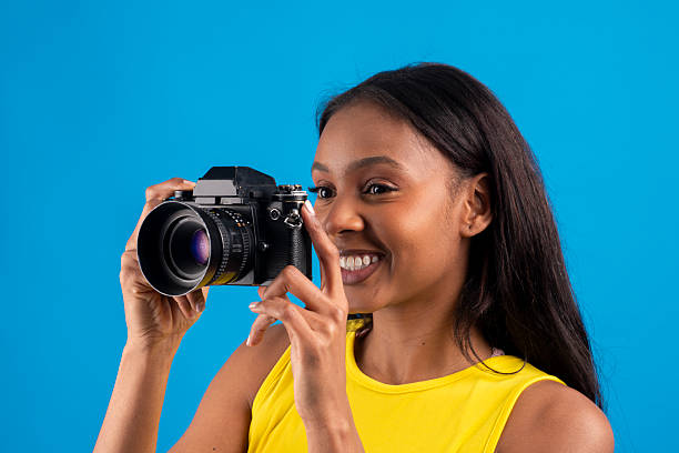 istock Young photographer taking pictures with analog camera on blue background 2227709473