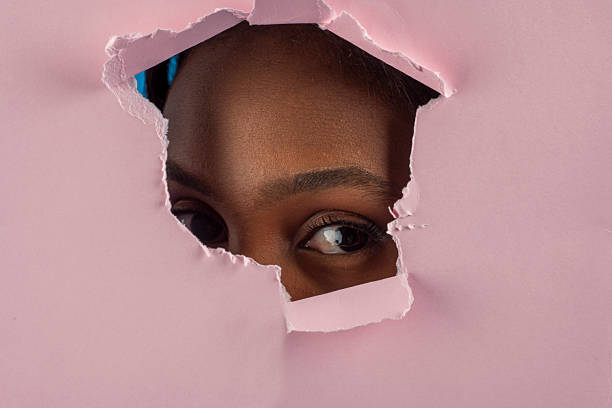 istock Curious young woman peeking through torn pink paper 2227709843