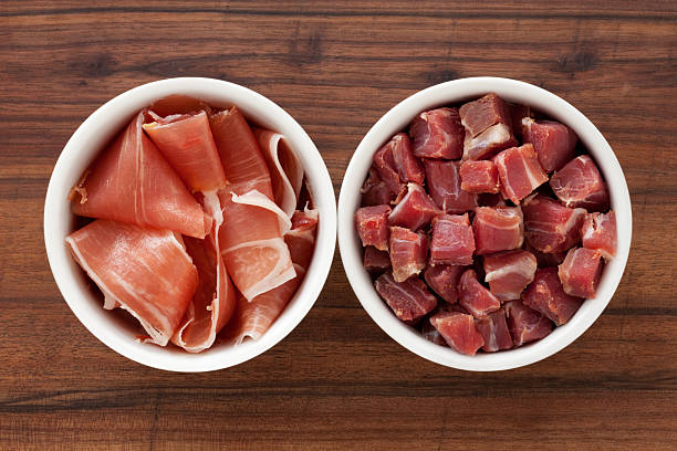 Top view of two bowls side by side with sliced and cubed prosciutto ham