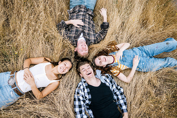 Group of happy children sit on the floor with joined hands and looking at camera