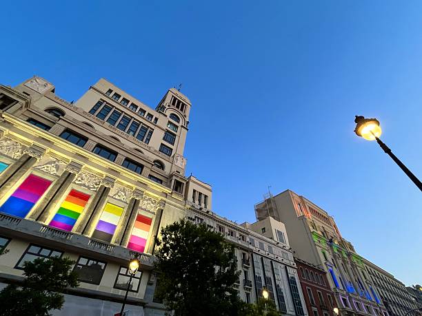 Madrid, Spain - July 6, 2025: Vibrant rainbow colors illuminating historic buildings on Calle de Alcalá in Madrid during the Gay Pride celebration, with a clear blue sky enhancing the festive atmosphere.