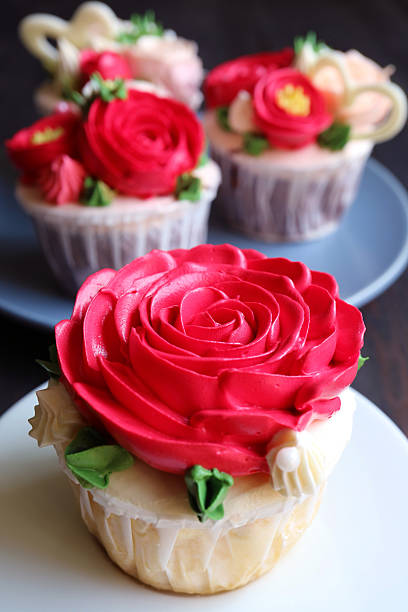 Closeup of a gorgeous red rose frosting cupcake with other cupcakes in the backdrop