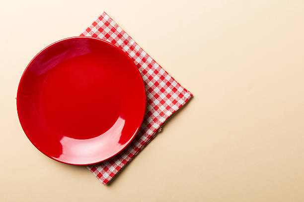 istock Top view on colored background empty round red plate on tablecloth for food. Empty dish on napkin with space for your design 2227720831