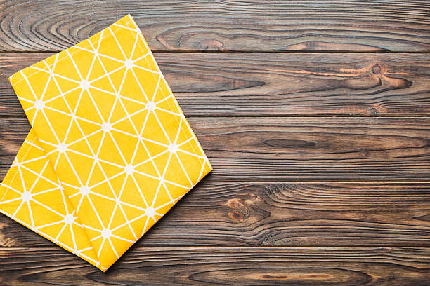 istock top view with yellow empty kitchen napkin isolated on table background. Folded cloth for mockup with copy space, Flat lay. Minimal style 2227720876