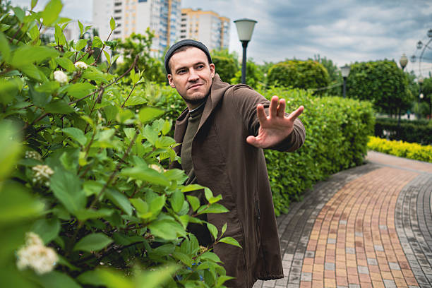 Handsome Man Dancing Enthusiastically in a Lush Green Park on a Cloudy Afternoon.