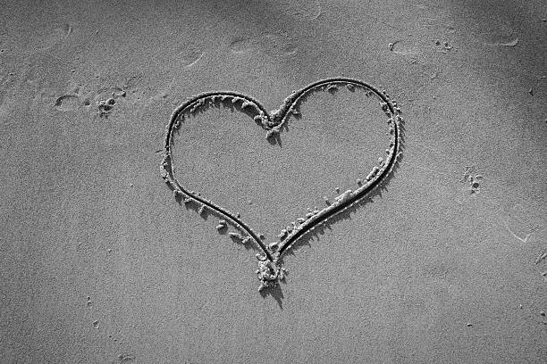 Heart shape drawn on the sand at the beach, symbolizing love and romance, with wide copy space. Minimal and emotional coastal scene.