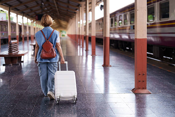 istock Asian older woman traveler journey train station platform pulling suitcase backpack vacation retirement adventure 2227725929