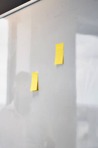 istock Two yellow sticky notes hanging on a whiteboard in an office 2227731169
