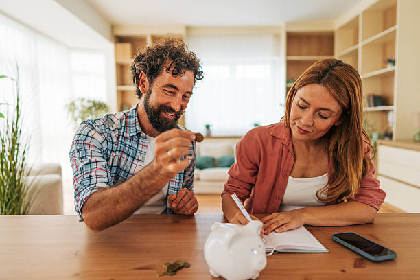istock Couple saving money at home using piggy bank and notebook 2227735741