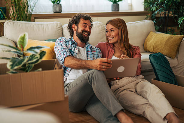 istock Couple watching laptop and laughing while moving into new home 2227739000