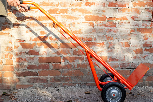 Man with hand truck near brick wall. Device with platform for transporting cargo.