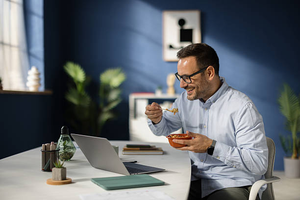 Happy businessman eating breakfast while working from home office