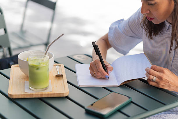 40-year-old businesswoman writes in a notebook while having a healthy breakfast at an outdoor café