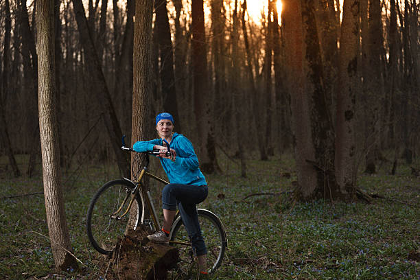 A serene outdoor scene of a woman walking her bicycle along a forest path, surrounded by lush greenery and natural light. The image evokes a sense of tranquility, eco-conscious travel
