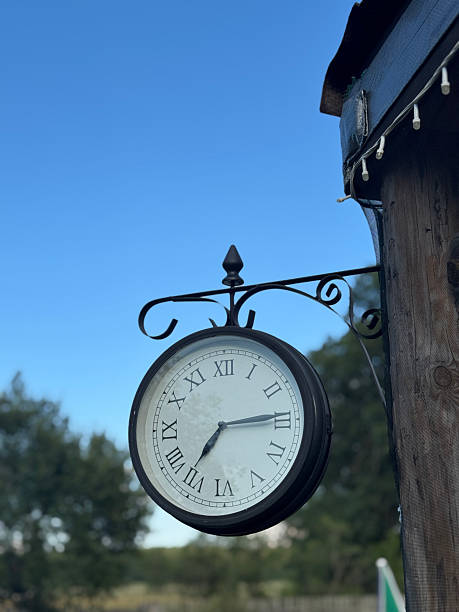 istock Vintage clock on a wooden structure. Dial with Roman numerals. 2227743541
