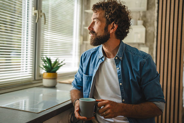 istock Thoughtful man drinking coffee and looking out the window in kitchen 2227743694
