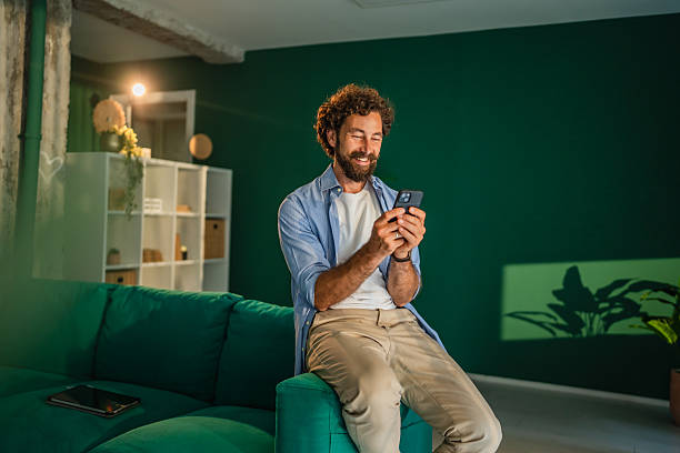 Start up founder enjoying good news on smart phone sitting on sofa in modern office
