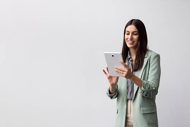istock Professional businesswoman smiling, using digital tablet, white background, embodying workplace confidence and modern technology interaction 2227749230