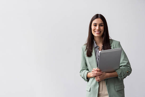 istock Professional businesswoman smiling, holding tablet while posing against white background 2227753708
