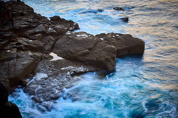 View of ocean waves breaking on rocky beach, Cornwall, UK with long exposure time
