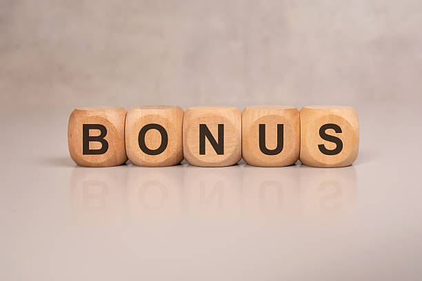 istock Wooden blocks spelling BONUS on a glossy desk surface with reflection 2227757871