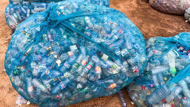 Plastic bottles in large mesh bags, ready for recycling. Waste management and environmental pollution, global crisis and the need for sustainability.
