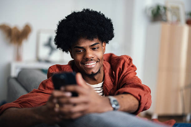 istock Smiling Individual Relaxing Indoors and Engaged on Smartphone 2227767632