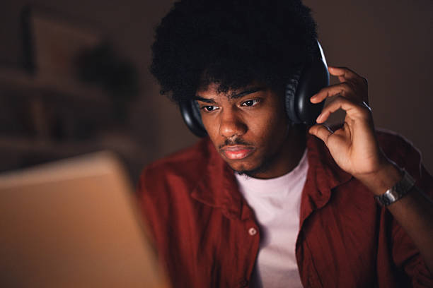 istock Focused Teenager Wearing Headphones Studying or Working on a Computer at Night 2227767634