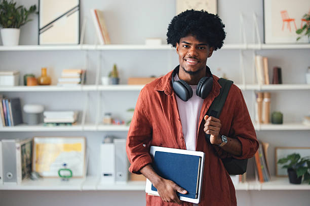 istock Smiling Student at Home Holding Notebook in Study Environment with Bookshelves 2227767660