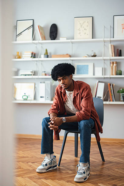 istock Young Person Sitting Thoughtfully in a Stylish Home Interior 2227767731