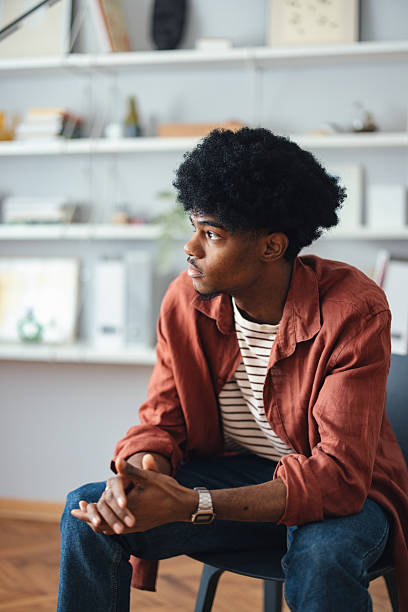 istock Young Man Sitting Thoughtfully in a Modern Home Interior 2227767737