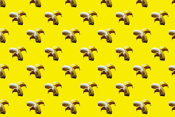 Pattern of open ripe yellow bananas on bright yellow background. Fruit background summer tropical pattern.