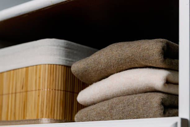istock Stylish cashmere sweaters on a shelf in a white closet. 2227775994