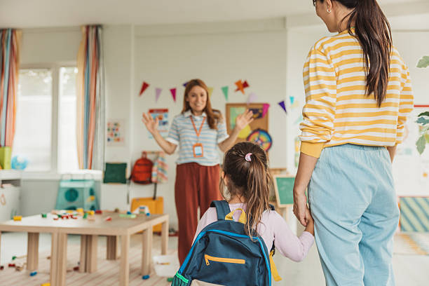 istock Preschool teacher in classroom greeting new student 2227776934