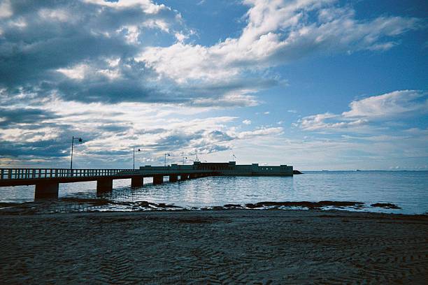 istock Tranquil pier extending into the calm sea under a cloudy sky. 2227777545