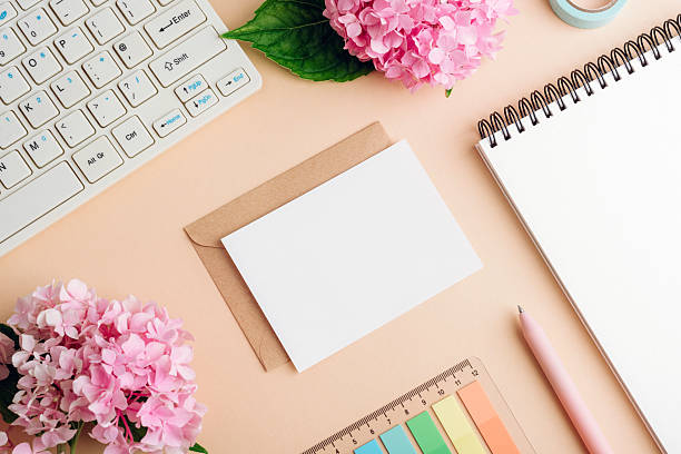 istock Home office desktop with computer keyboard, notepad, envelope with blank card, pen, color palette and hydrangea pink flowers on beige background. Top view, flat lay, mockup 2227780127