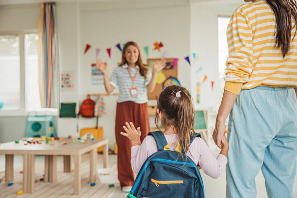 istock Preschool teacher in classroom greeting new student 2227781057