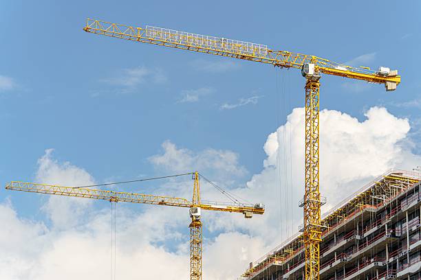 istock Against the blue sky, two construction cranes are building 2227781969