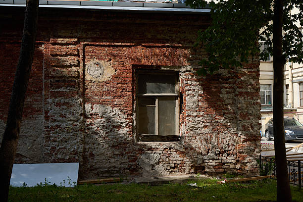 A rustic brick wall with a window, enhanced by shadows and natural elements from the surrounding environment