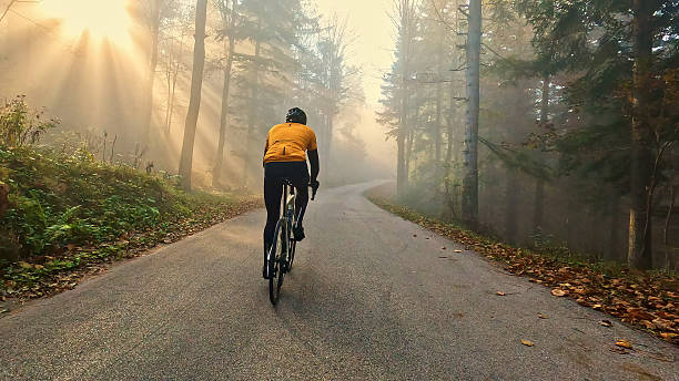 istock Cyclist rides down foggy, leaf-covered road 2227783978