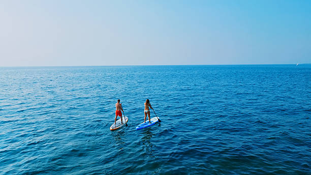 istock Couple paddleboarding on calm blue ocean 2227784019