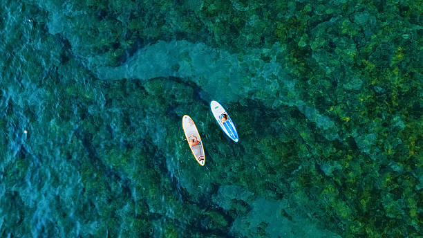 istock Two people paddleboarding in clear blue water 2227784027