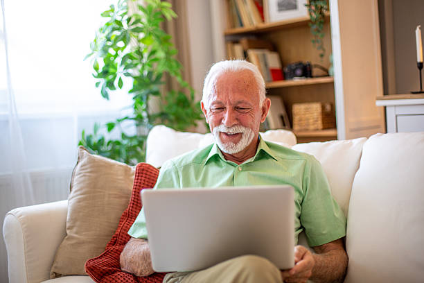istock Senior man using laptop and relaxing on sofa at home 2227784986