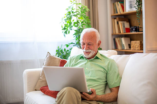 istock Senior man sitting on sofa using laptop at home 2227784987