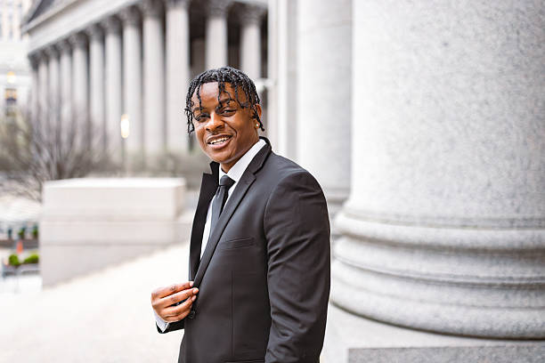 Young professional man in suit smiling confidently outside a courthouse, representing success and ambition.