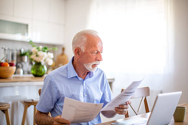 istock Senior man carefully reviewing documents at home 2227785213
