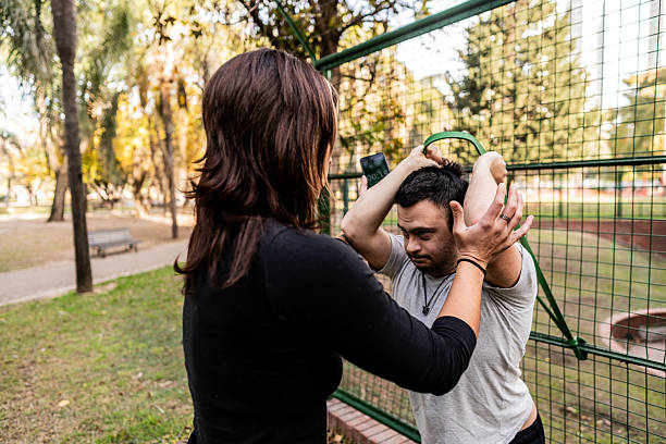istock Young man with down syndrome doing exercise with trainer at public park 2227786945