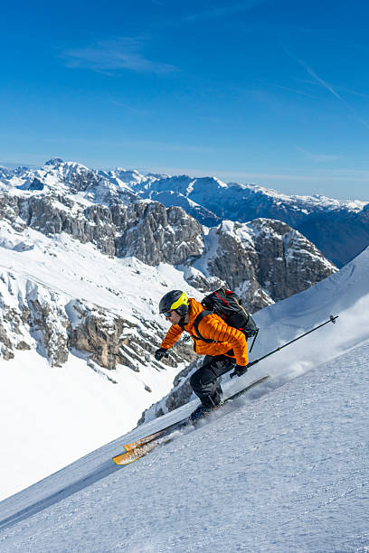 istock Athletic Skier Carving Down Steep Alpine Slope With Snow-Covered Mountain Range Background 2227788425