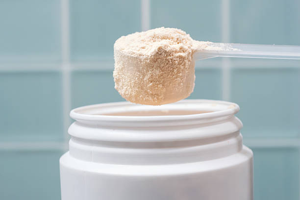 istock Protein powder in scoop and plastic jar on blue tile background close-up. 2227791218